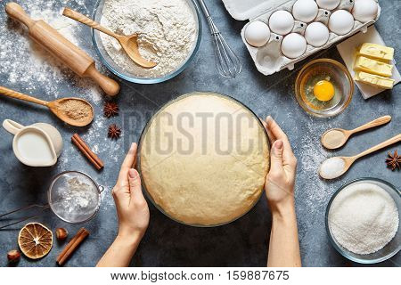 Hands working with dough preparation recipe bread, pizza or pie making ingridients, food flat lay on kitchen table background. Butter, milk, yeast, flour, eggs, sugar pastry or bakery cooking.