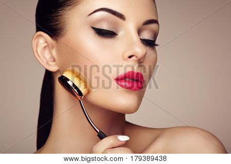 Makeup artist applies skintone with brush. Beautiful woman face. Perfect makeup. Skincare foundation. Brushes makeup artist